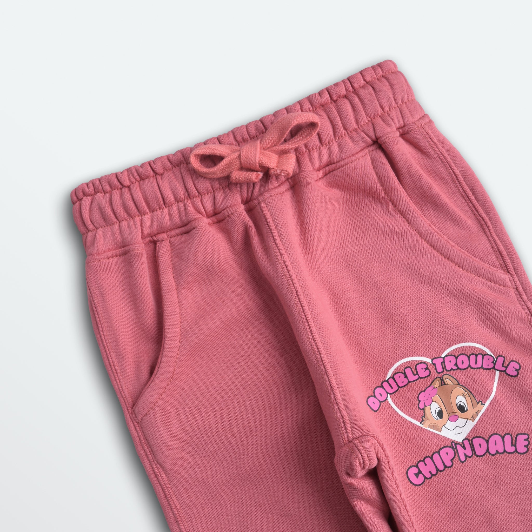 Pink sweatpants with 'Double Trouble Chipm Kale' design on a light gray background